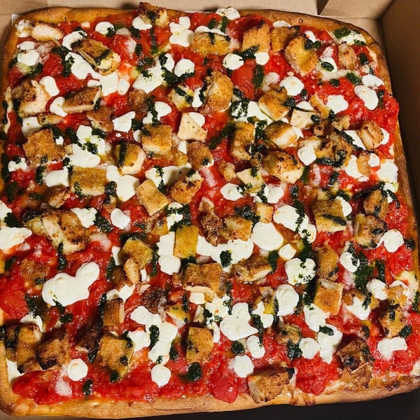 A square Soprano's Pizza with red sauce, mozzarella, pesto, and crispy chicken pieces.