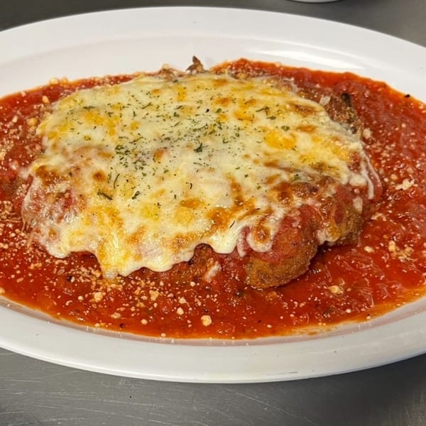 Chicken Parmesan with melted mozzarella cheese and red sauce on a white plate.