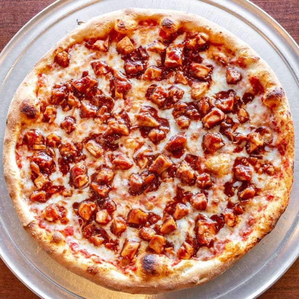 Soprano's Pizza's BBQ chicken pizza, topped with mozzarella cheese and barbecue sauce, on a metal tray.
